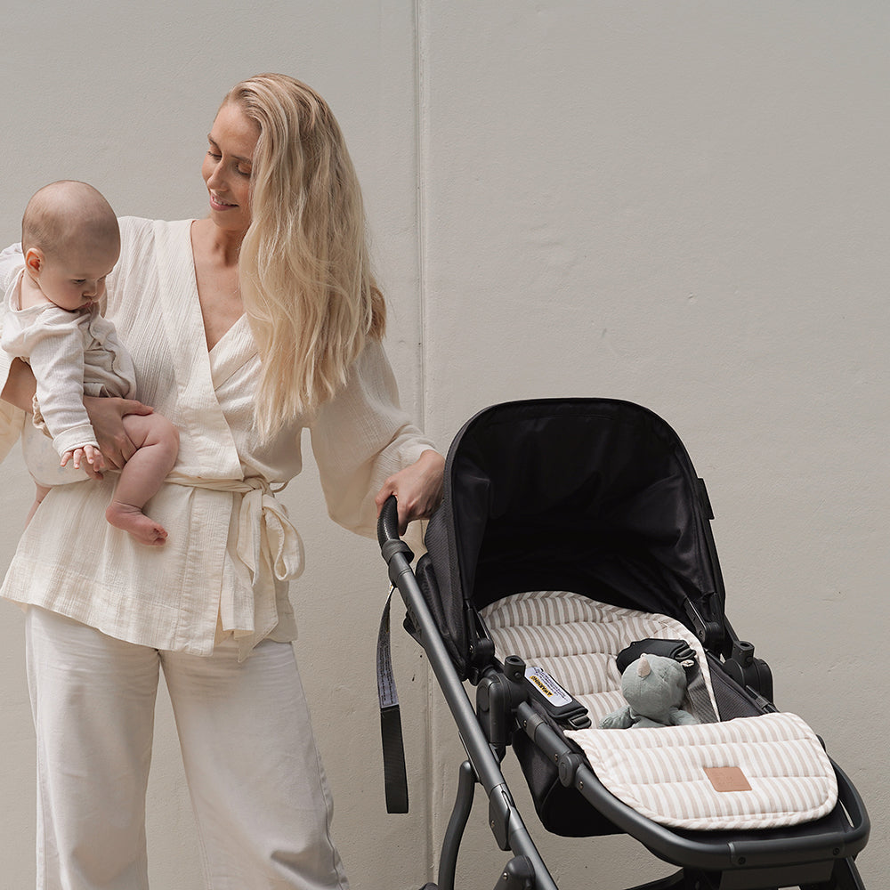 Mother holding baby and pushing a buggy