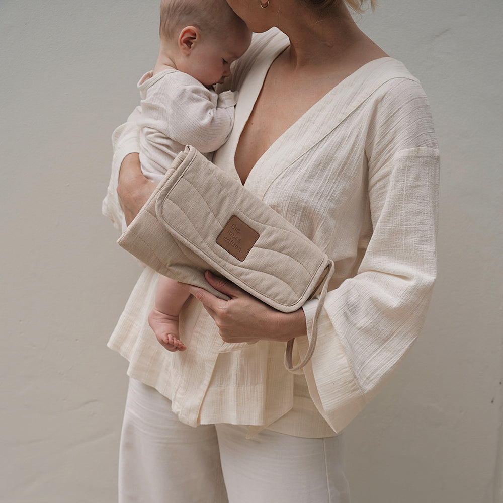 Mother snuggling baby and holding a bag