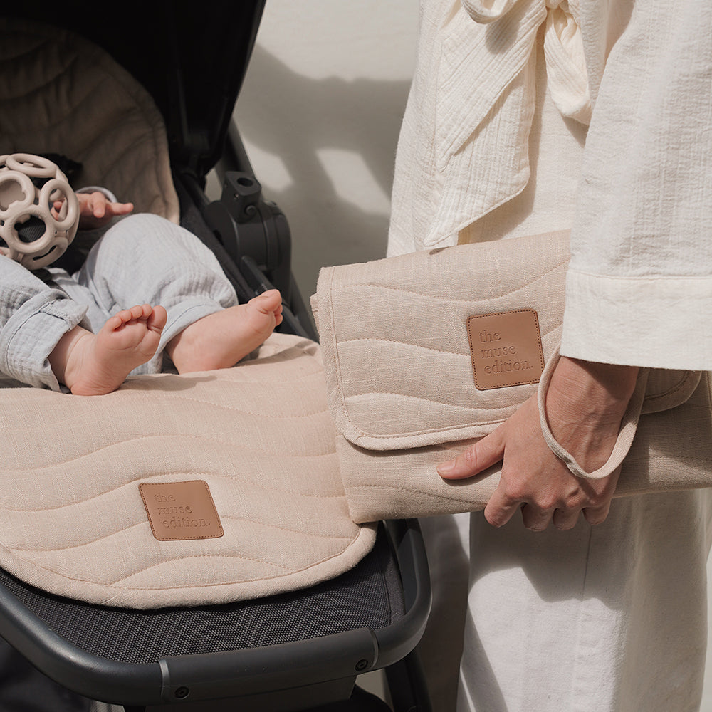 Mother holding change mat bag next to a buggy