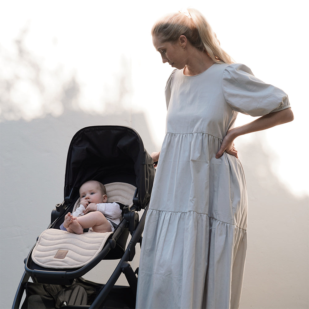 Mother standing next to a pram with a baby in it